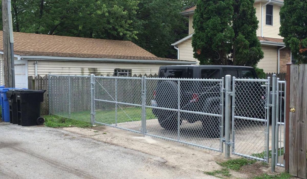 a black car parked behind a chain-link fence