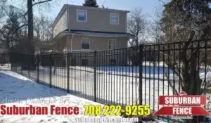 Residential metal fence in snowy yard showing signs of winter damage, highlighting the need for fence repair.