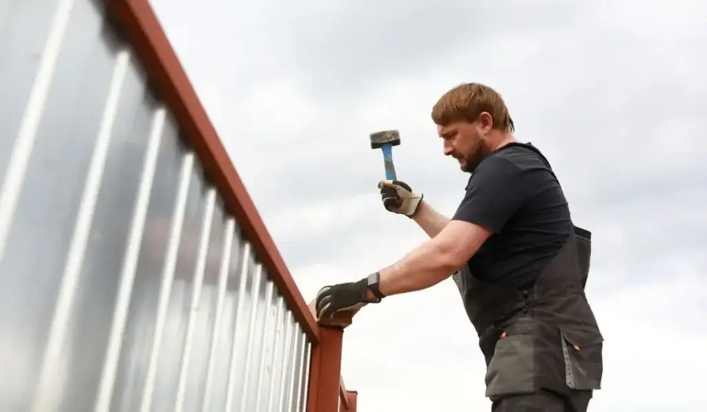 Chicago homeowner struggling with a DIY fence installation on a metal frame, highlighting risks of doing fencing without professional help.