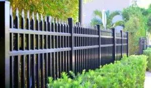 Black metal security fencing with anti-climb spikes in landscaped area.