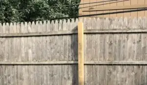 Fence warping in Chicago backyard caused by summer heat, showing cracked wood and structural stress on panels.