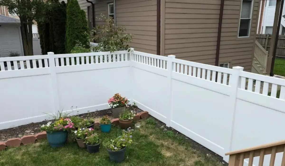 White vinyl fencing designs surround a backyard garden with potted flowers and lattice-top privacy panels.